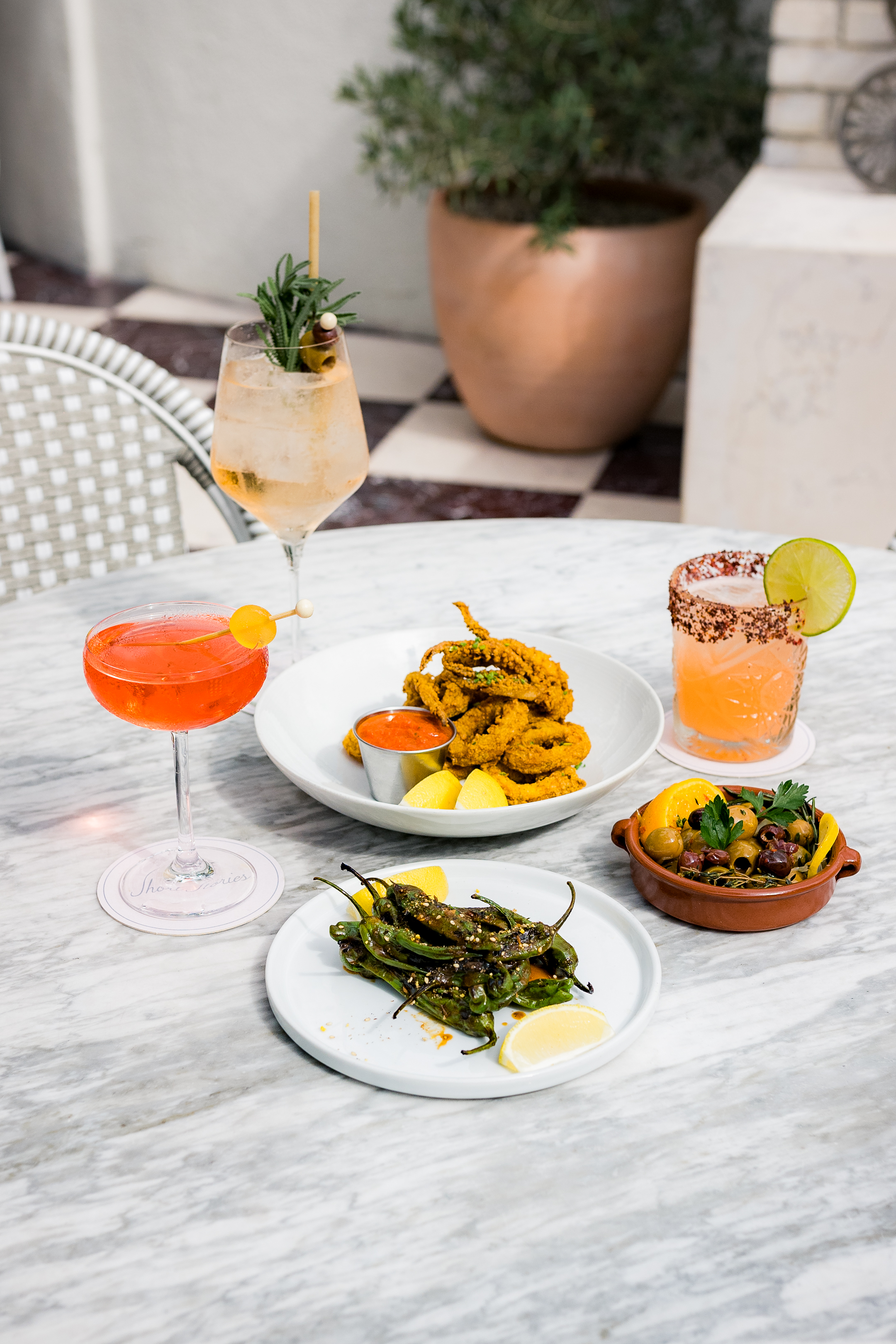 A table set with various cocktails and dishes of food.