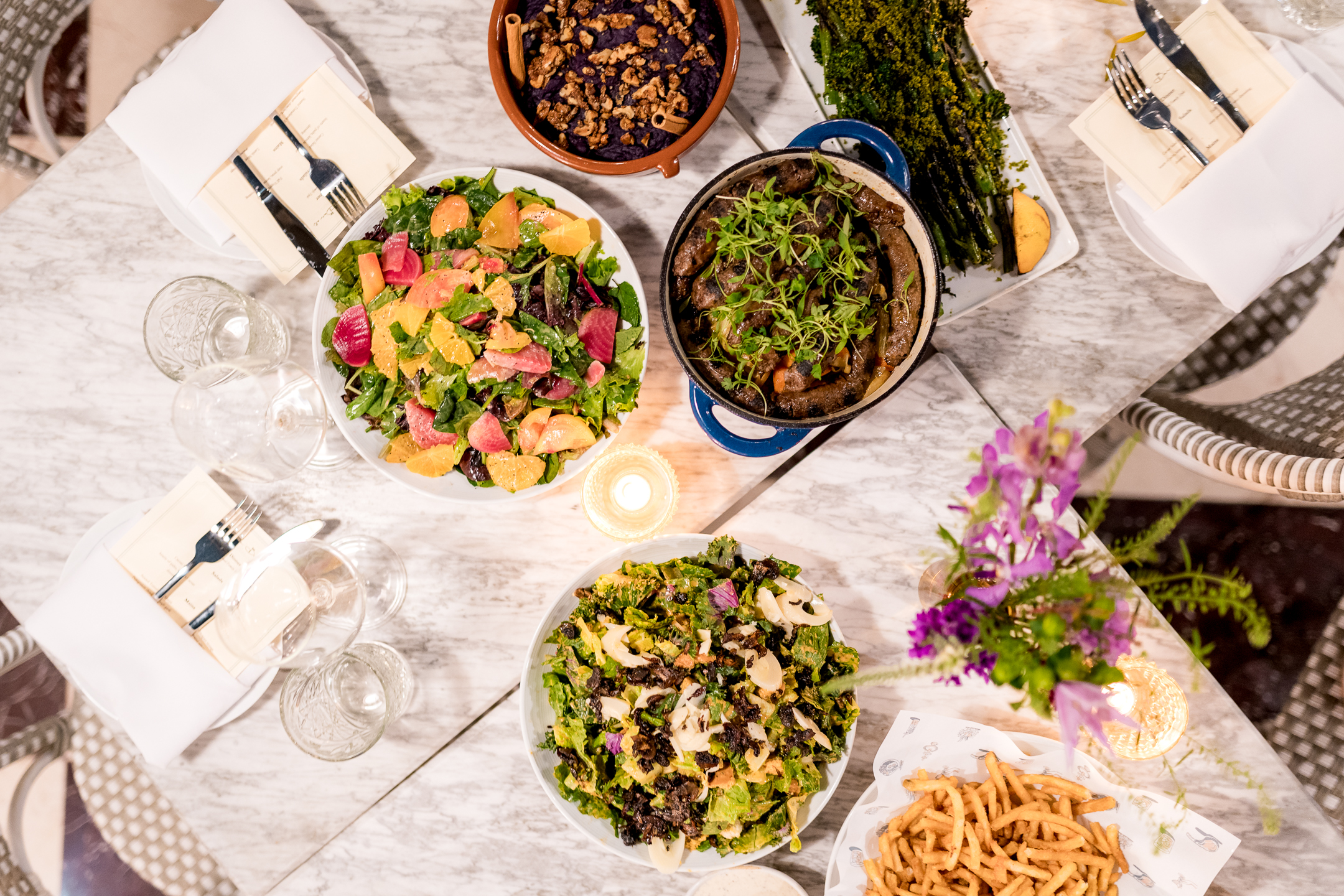 a table set with various dishes of food and glasses