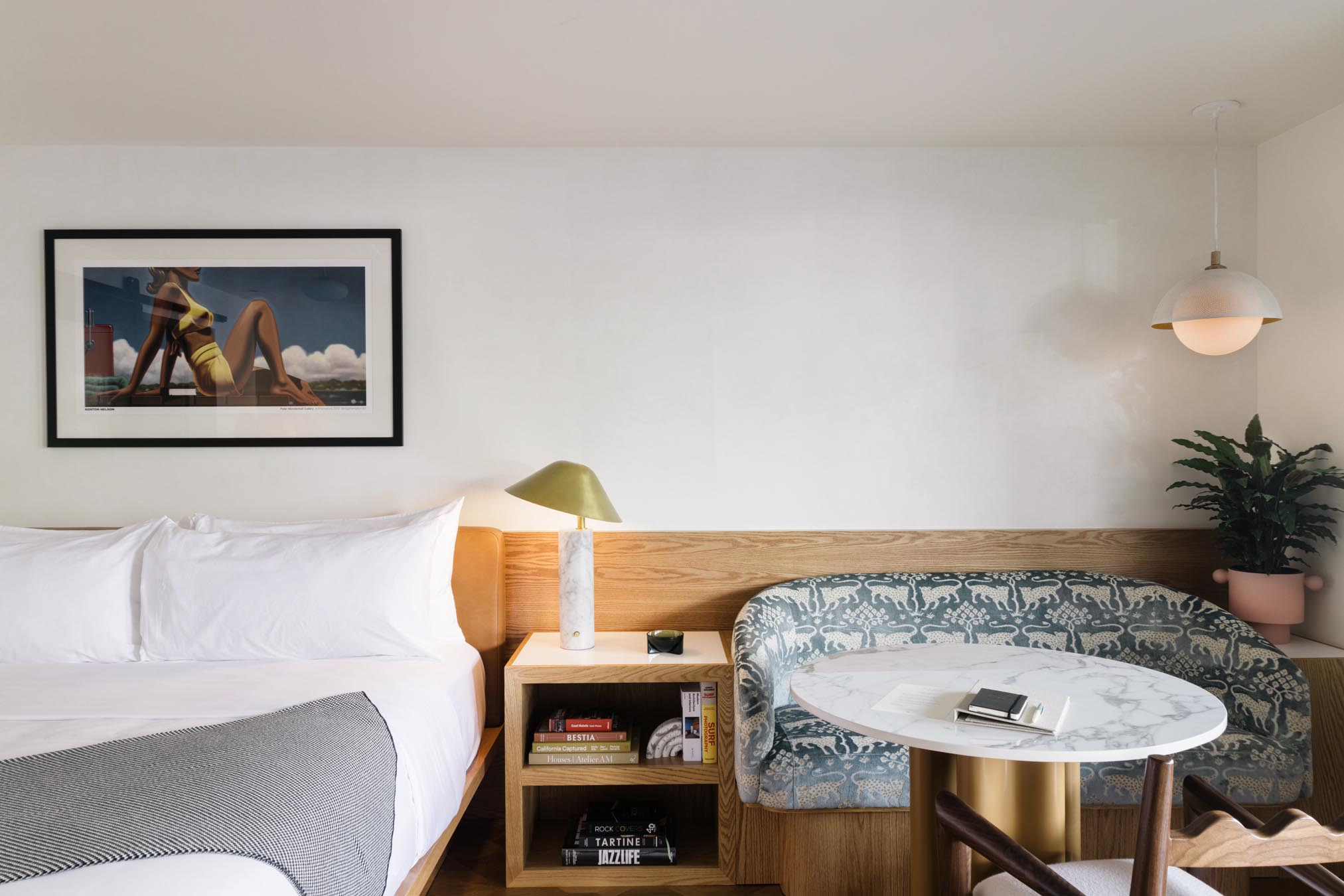 A hotel room with a bed, sofa, table, and artwork