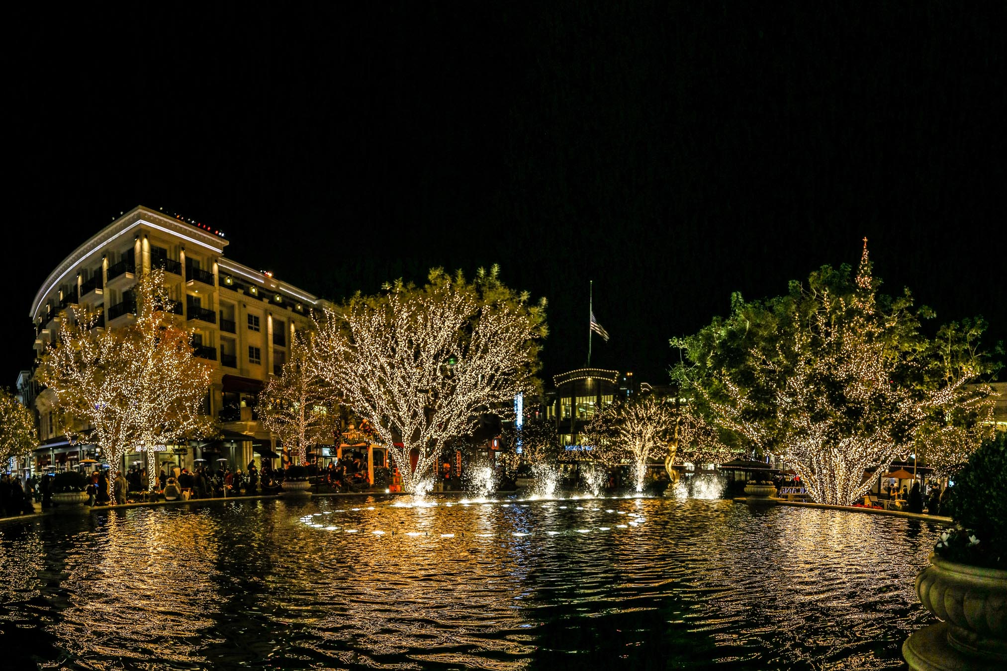A nighttime view of a building and fountain with trees and lights.